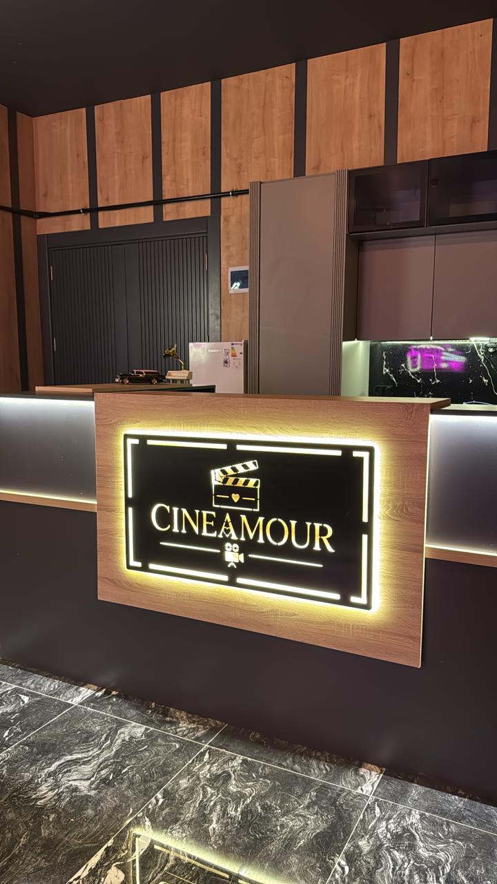 Cineamour resepsiyonu: ahşap bankonun üzerinde ışıklı altın logo